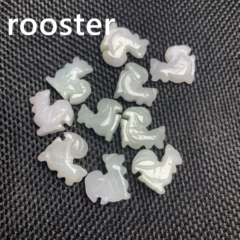 Pode incluir: Uma cole&ccedil;&atilde;o de pequenas figuras de galo esculpidas em tons de branco e verde p&aacute;lido. A palavra "rooster" est&aacute; impressa em branco no topo. As figuras est&atilde;o dispostas sobre uma superf&iacute;cie escura e texturizada.