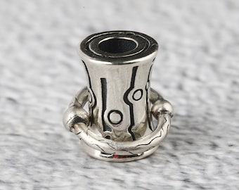 Könnte beinhalten: Eine silberne Metallperle mit einem strukturierten Design und einem Ring in der Mitte. Die Perle hat ein schwarz-weißes Muster.