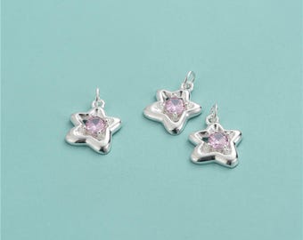 May include: Three silver star-shaped charms with pink crystal centers. The charms have a delicate, intricate design.