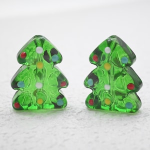 May include: Two green Christmas tree-shaped ornaments with colorful dot decorations. The ornaments are made of a translucent material, allowing light to pass through. The dots are red, white, yellow, and blue.