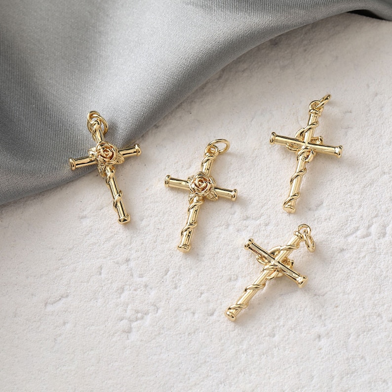 May include: Four gold-tone cross charms with a rose design in the center. The crosses are intricately detailed and have a twisted rope design.