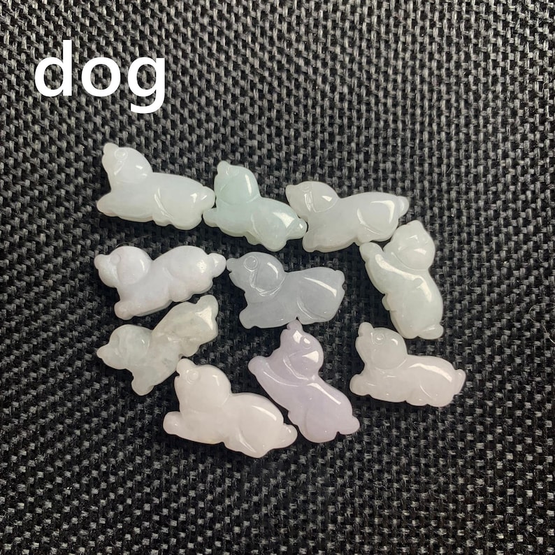Pode incluir: Uma cole&ccedil;&atilde;o de pequenas figuras de c&atilde;es esculpidas em v&aacute;rios tons de branco, verde e roxo. A palavra "dog" est&aacute; escrita em branco no canto superior esquerdo. As figuras est&atilde;o sobre uma superf&iacute;cie escura e texturizada.