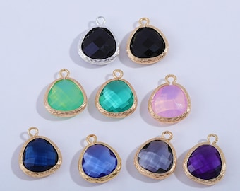 May include: A collection of teardrop-shaped gemstone pendants in various colors, including black, green, blue, and purple. Each pendant has a faceted surface and is framed with a gold-colored metal. The pendants are designed for jewelry making.