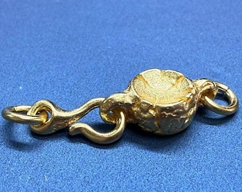 May include: A gold-toned metal clasp with a textured, round design. The clasp has a hook on one end and a ring on the other.