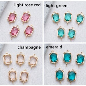 May include: Four sets of gold-toned metal charms with a rectangular glass stone. The stones are in four colours: light rose red, light green, champagne, and emerald.