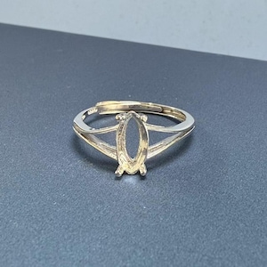 Könnte beinhalten: Silberner Ringrohling mit ovaler Fassung. Der Ring ist mit einer geteilten Schiene gestaltet.