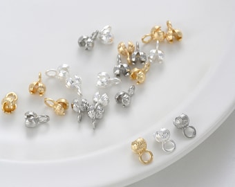 May include: Assortment of gold, silver, and brass metal bead caps with a decorative design. The bead caps have a small loop at the top for attaching to jewelry.