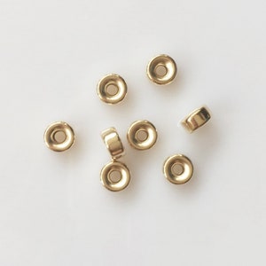 May include: Eight gold-colored metal spacer beads. The beads are round with a hole in the center. They are perfect for adding a touch of elegance to jewelry projects.