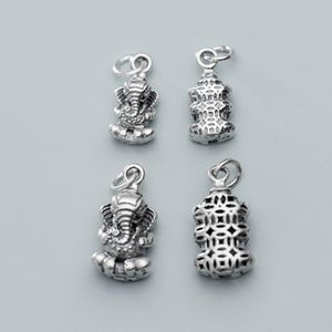 May include: Four silver charms, two featuring a detailed elephant design and two featuring a geometric pattern.
