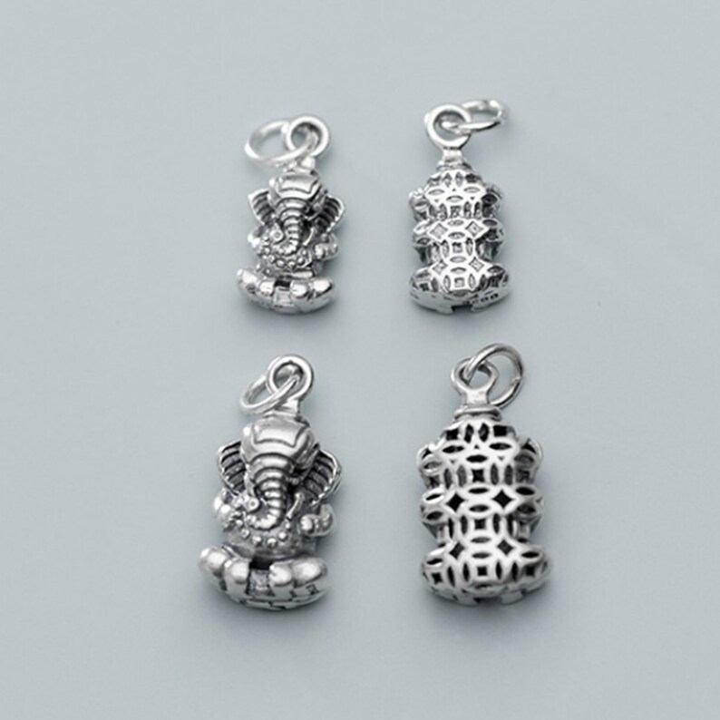 May include: Four silver charms, two featuring a detailed elephant design and two featuring a geometric pattern.