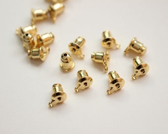 May include: A group of 14 gold-colored earring backs. The backs are small and round, with a small loop on the top. They are designed to be used with stud earrings.