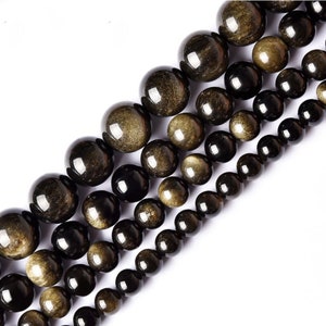 May include: A strand of black and gold beads with a shimmering, iridescent finish. The beads are round and smooth, and they are arranged in a graduated size, with the largest beads at the top and the smallest beads at the bottom.