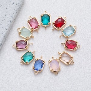 May include: Assortment of 10 colourful glass gem charms with gold-tone metal settings and jump rings. The gems are in various colours, including red, pink, blue, green, and purple.