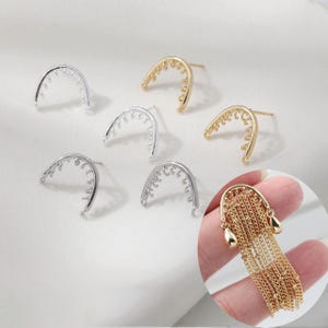 Pode incluir: Uma variedade de componentes de brincos em tons de prata e ouro. Os componentes incluem arcos curvos de costas abertas com detalhes decorativos e um brinco acabado com franjas de corrente e detalhes de gota.