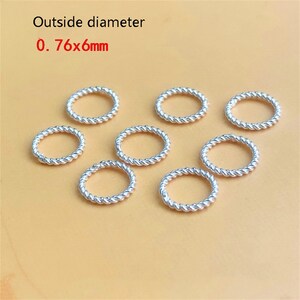 以下が含まれることがあります： 銀色のねじれた金属リングのコレクション。上部には「Outside diameter 0.76x6mm」の文字が表示されています。リングは薄茶色の表面に配置されています。リングのサイズは0.76mm x 6mmです。