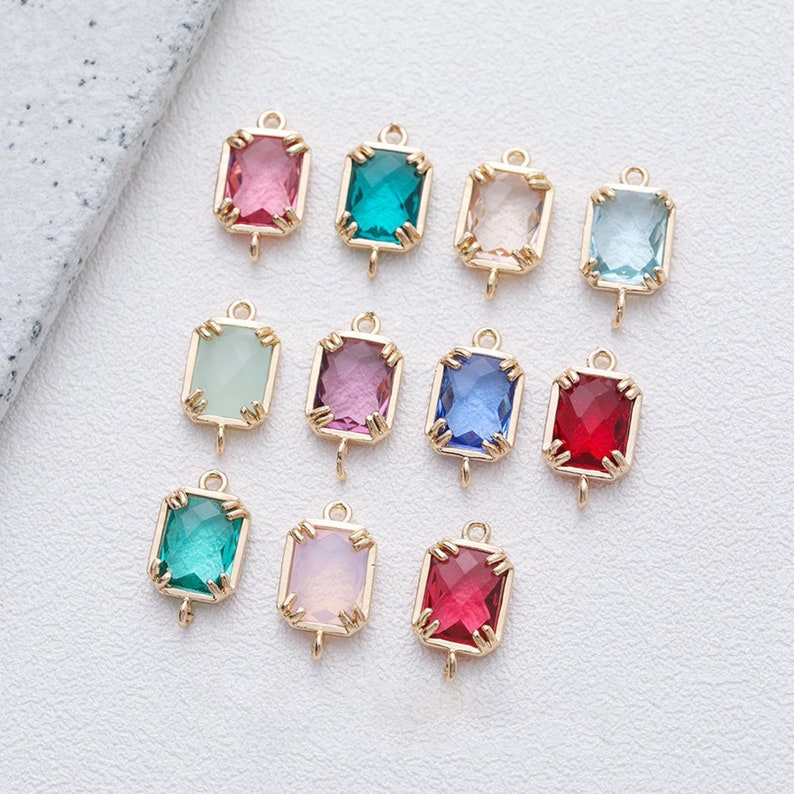 May include: Assortment of 10 gold-toned charms featuring faceted glass stones in various colours, including pink, green, blue, red, and clear. Each charm has a loop for attaching to jewellery or other crafts.