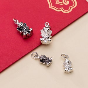 May include: Four silver charms in the shape of the Hindu deity Ganesha. The charms are detailed and have a textured finish.