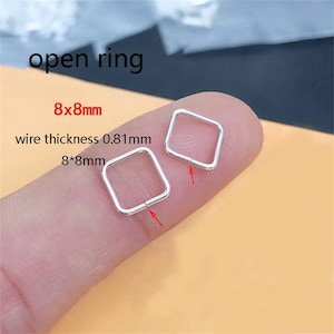 Puede incluir: Dos pequeños anillos cuadrados y abiertos de metal plateado. Los anillos miden 8x8mm con un grosor de alambre de 0,81mm. El texto "open ring" está encima de los anillos. Los anillos se muestran en un dedo.