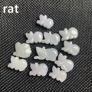 Pode incluir: Uma cole&ccedil;&atilde;o de pequenas figuras de rato esculpidas em jade em v&aacute;rias poses. As figuras s&atilde;o de uma cor verde-branca p&aacute;lida e transl&uacute;cida e est&atilde;o dispostas sobre uma superf&iacute;cie texturizada cinza escuro. A palavra "rat" est&aacute; no canto superior esquerdo.
