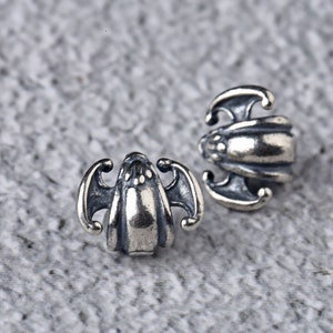 May include: A pair of silver earrings with a bat design. The earrings are small and delicate, and they would make a great gift for a friend or loved one.