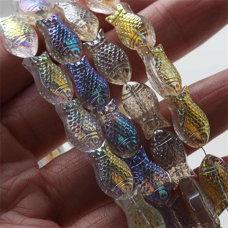 May include: A strand of iridescent glass fish beads. The beads are clear with a rainbow sheen and have a detailed fish design.