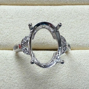 Puede incluir: Engaste de anillo de plata con un bisel de forma ovalada y pequeñas piedras transparentes en la banda.