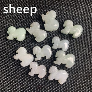 Pode incluir: Uma cole&ccedil;&atilde;o de pequenas figuras de ovelhas verdes claras e brancas. A palavra "sheep" est&aacute; escrita em letras brancas no canto superior esquerdo. As figuras s&atilde;o esculpidas com detalhes e dispostas sobre uma superf&iacute;cie texturizada cinza escuro.