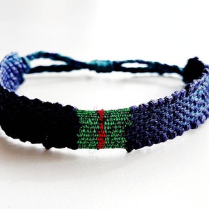 May include: A blue, green, and red woven friendship bracelet with a knot at the end.