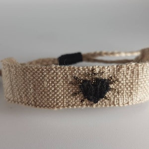 The "Heart of the Black Virgin": Hand-woven bracelet, twine linen thread, black sacred heart embroidery in silk and gold and black lurex thread.