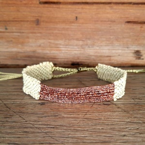Le &quot;Gipsy glow&quot; : Bracelet Holi, tissé à la main, en fil de raphia naturel, et fil lurex caramel. Fil de chaîne couleur or