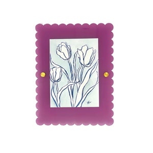 Puede incluir: Un marco morado con un borde festoneado y detalles dorados rodea un dibujo de línea blanca y azul de tulipes. El dibujo está firmado "K" en la esquina inferior derecha.