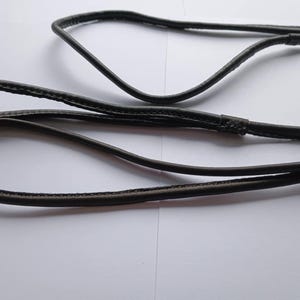 May include: A black leather dog lead with a loop handle and a metal clasp. The lead is made of a smooth, durable material. The lead is approximately 122 cm long.