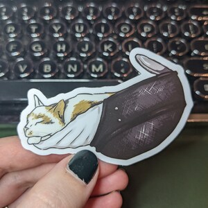 May include: A white and brown cat is sleeping inside a black and white patterned boot. The boot is curled up and the cat's head is resting on the top of the boot.