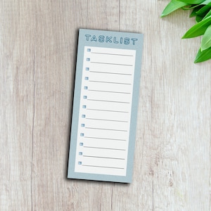 May include: A blue checklist notepad with the word "TASKLIST" printed in a blue outlined font at the top. The notepad has 15 lines with checkboxes next to each line.