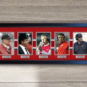 May include: A framed collage of five headshots of Ohio State University football coaches. The coaches are Woody Hayes, Earle Bruce, Jim Tressel, Urban Meyer, and Ryan Day. Each coach is pictured in a different pose and wearing a different outfit. The frame is black with a red background.