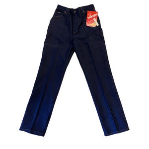 May include: Dark blue Wrangler jeans with a high waist and straight leg. The jeans have a classic five-pocket design, a zipper fly, and a Wrangler tag attached. The stitching is a contrasting yellow color.