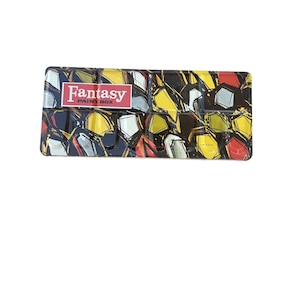 May include: A rectangular paint box featuring a vibrant geometric pattern in yellow, red, black, and white. The box has a red and white label that reads "Fantasy PAINT BOX". This paint box is designed for artists.