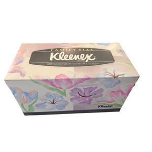 Op de afbeelding: Een rechthoekige Kleenex Brand familieverpakking gezichtstissues met een aquarel bloemenpatroon in roze, paarse en blauwe tinten. Het label aan de bovenkant vermeldt Family Size, Kleenex Brand, White Facial Tissue, 250 2-Ply Tissues, 21.8 x 21.3 cm.