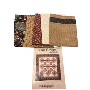 May include: A collection of fabric pieces in various patterns and colors, including floral, star, and geometric designs. The fabrics are arranged next to a pattern booklet titled "Star Flower Wall Quilt" by Thimbleberries.
