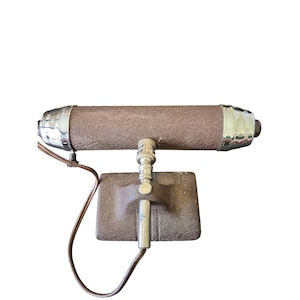 May include: A vintage brown and chrome wall-mounted lamp. The cylindrical lamp has chrome end caps and a rectangular base. A brown electrical cord extends from the lamp.