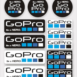Op de afbeelding: Een set van negen stickers met het GoPro-logo in zwart en wit met blauwe accenten. De stickers bevatten de tekst "GoPro" en "Be a HERO."