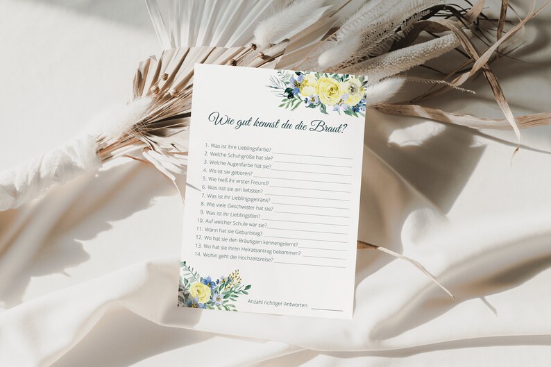 May include: A printable bridal shower game card with the title "Wie gut kennst du die Braut?" (How well do you know the bride?) and a list of 14 questions about the bride. The card is decorated with yellow and blue flowers.