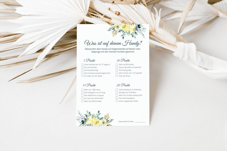 May include: A printable game card with a floral design and the text "Was ist auf deinem Handy?" (What's on your phone?). The card has a list of items to check on a phone, with points assigned to each item.