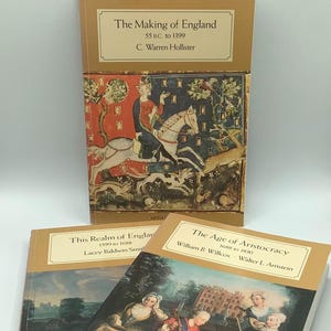 Puede incluir: Tres libros de tapa dura con cubiertas doradas y crema. El libro superior se titula "The Making of England" con una ilustración medieval. Los otros dos libros se titulan "This Realm of England" y "The Age of Aristocracy".