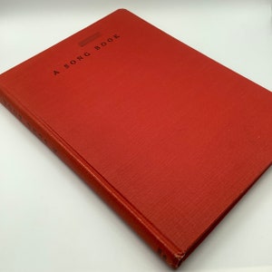May include: A red hardcover book with the title "A SONG BOOK" printed on the front cover.