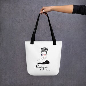 May include: White tote bag with black straps featuring a black and white illustration of a woman with a bun hairstyle wearing sunglasses with the American flag design. The text "Simplemente Boricua" is printed in black below the illustration.
