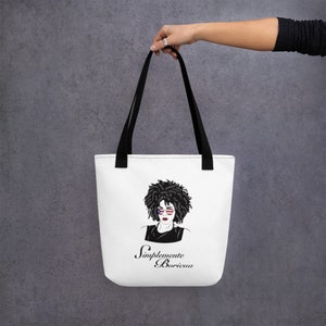May include: White tote bag with black straps featuring a black and white illustration of a woman with an afro wearing sunglasses with the American flag design. The text "Simplemente Boricua" is printed below the illustration.