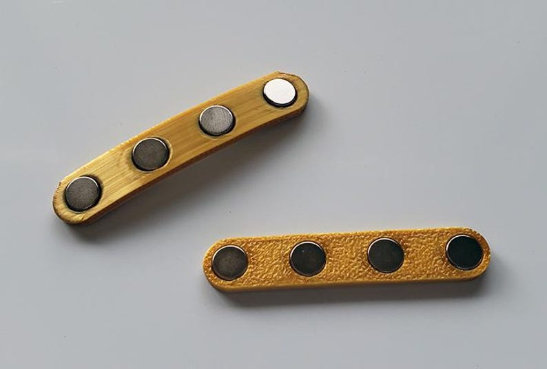Puede incluir: Dos correas de cuero amarillo con cierres magn&eacute;ticos plateados. Las correas tienen cuatro y cinco cierres magn&eacute;ticos, respectivamente.