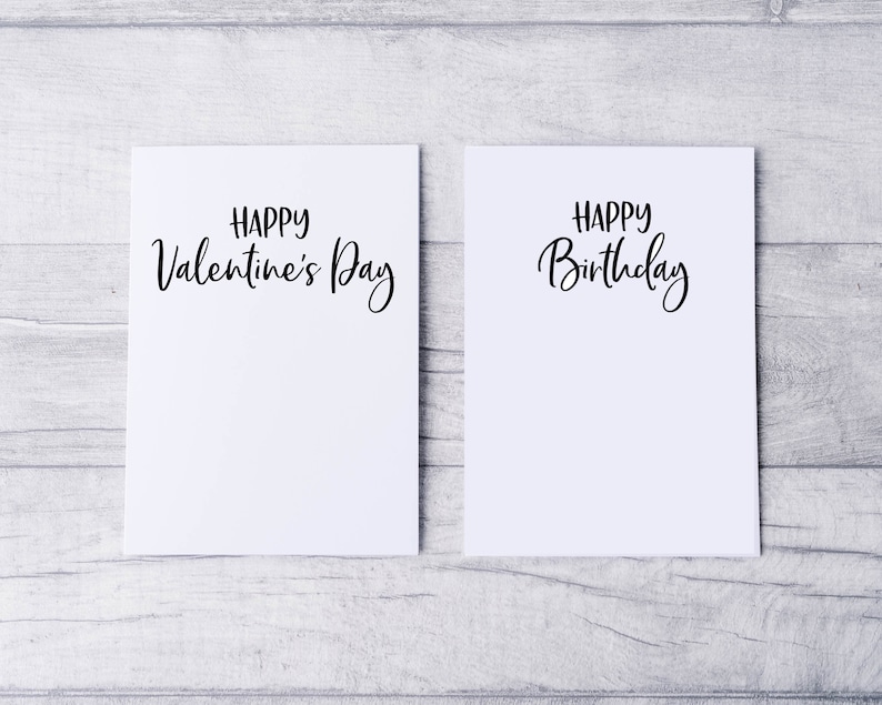 May include: Two blank white cards with black calligraphy. The card on the left says "Happy Valentine's Day". The card on the right says "Happy Birthday".