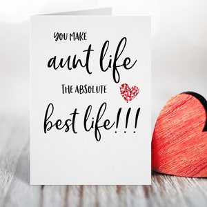 May include: A white card with black text that reads "You make aunt life the absolute best life!!!" with a red glitter heart. A red wooden heart is on the right side of the card.